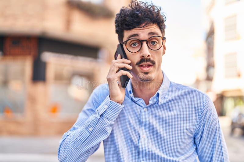 Young caucasian man talking on the smartphone with serious expression at street stock image