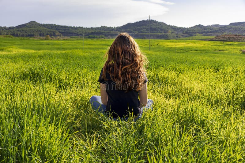 Young caucasian red-haired woman, with long hair and freckles, sitting on the grass in a yoga position. mindfulness, meditation royalty free stock photo Young caucasian red-haired woman, with long hair and freckles, sitting on the grass in a yoga position. mindfulness, meditation royalty free stock photo