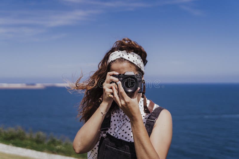 Young caucasian tourist woman outdoors taking pictures with a reflex camera on a windy and sunny day. Lifestyle, travel and royalty free stock image Young caucasian tourist woman outdoors taking pictures with a reflex camera on a windy and sunny day. Lifestyle, travel and royalty free stock image