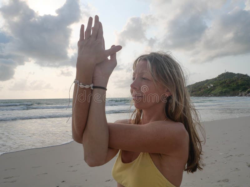 Young caucasian woman practice eagle yoga pose in seaside at sunrise stock photography Young caucasian woman practice eagle yoga pose in seaside at sunrise stock photography