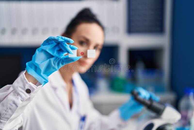 Young caucasian woman scientist using microscope looking sample at laboratory stock image