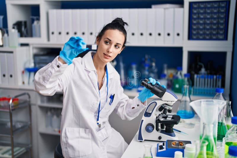 Young caucasian woman scientist using microscope looking sample at laboratory royalty free stock image