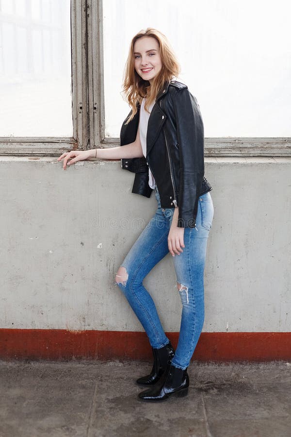 Young Caucasian Woman Stands In White T-Shirt, Black Leather Jacket, Blue  Jeans Stock Photo - Image Of Lady, Beautiful: 219752850