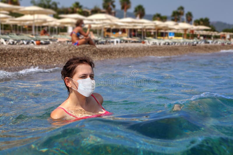 Young woman swims in the sea in a face mask