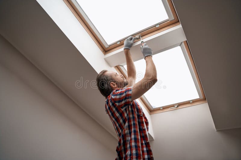 Young caucasian worker screwing skylight window handle stock images