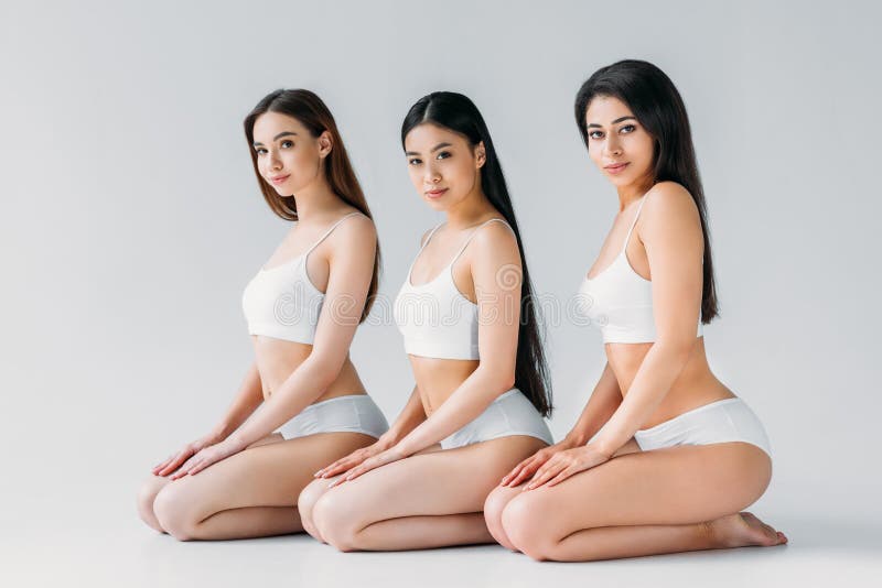 Young charming multicultural women posing in white underwear