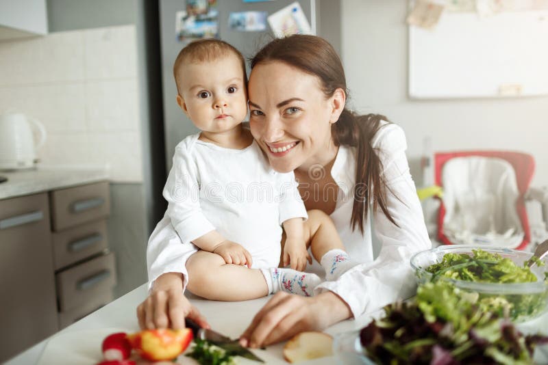 Young cheerful family of mother and newborn baby boy hugging, smiling, posing for family photo in kitchen. Family royalty free stock photos Young cheerful family of mother and newborn baby boy hugging, smiling, posing for family photo in kitchen. Family royalty free stock photos