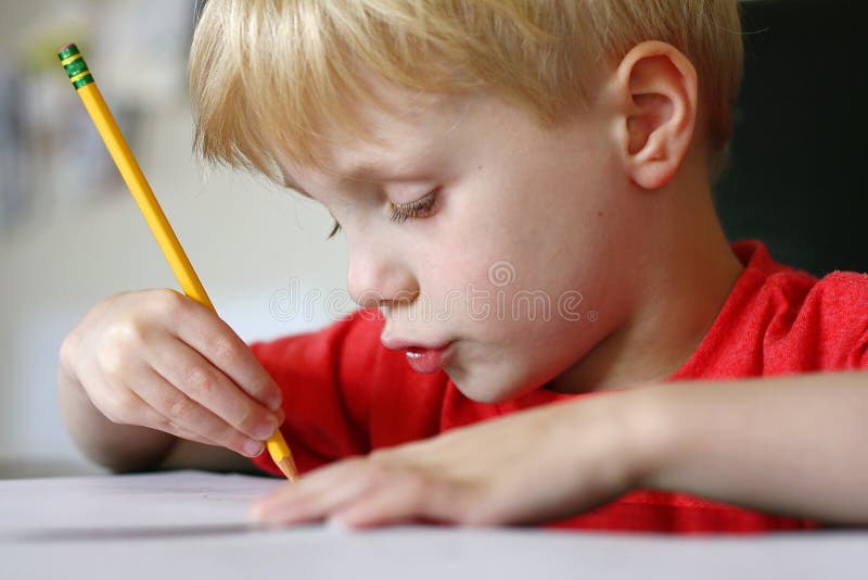 Young Child Drawing with Paper and Pencil stock image