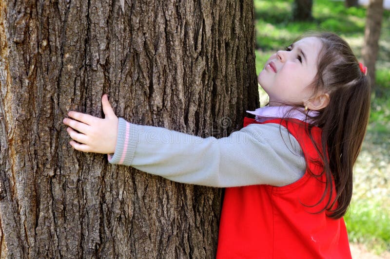 Young child hugging a tree.