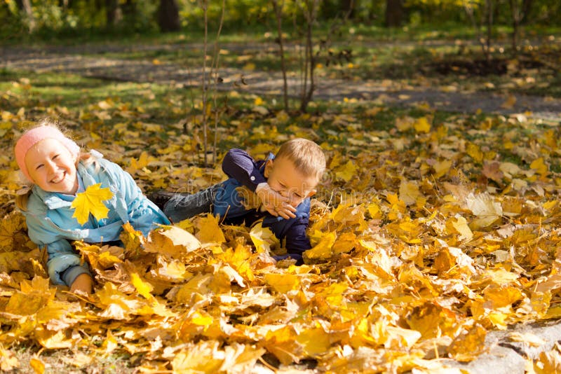 Young children playing in autumn leaves