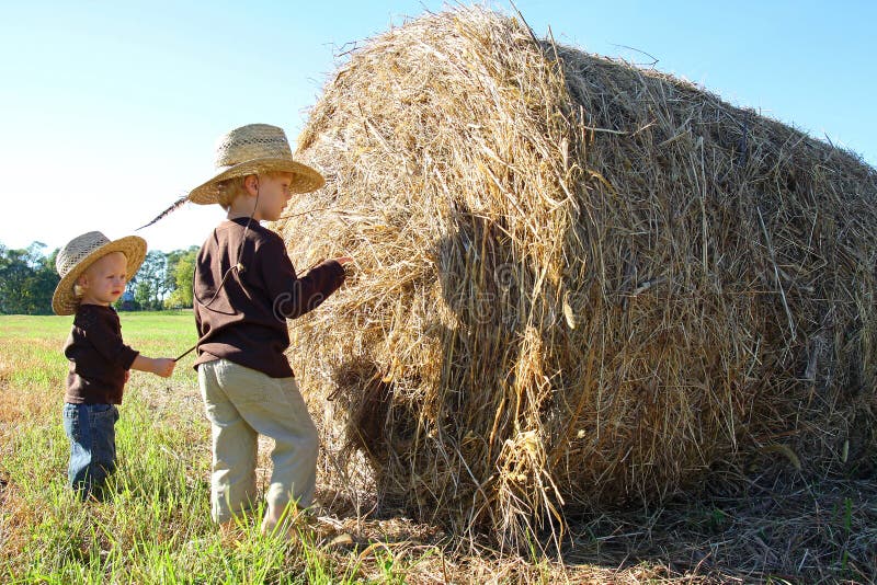 Young Children Playing on Farm with Hay Bale