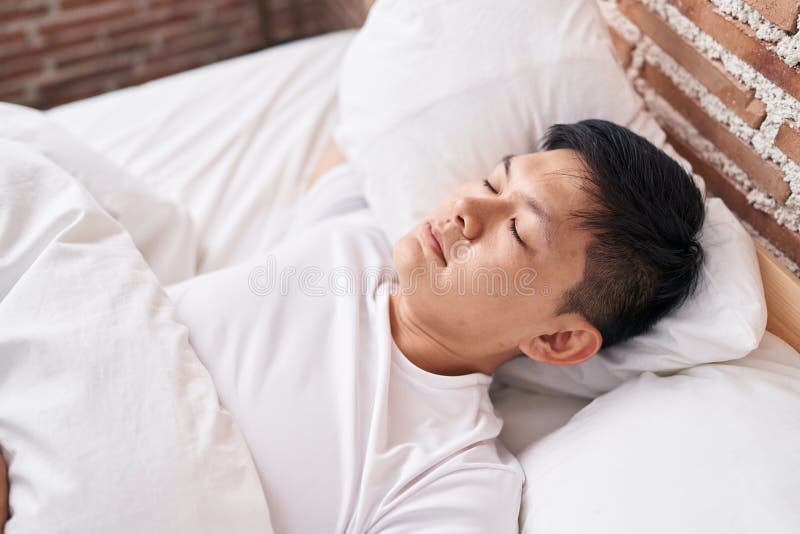 Young Chinese Man Lying on Bed Sleeping at Bedroom Stock Photo Image