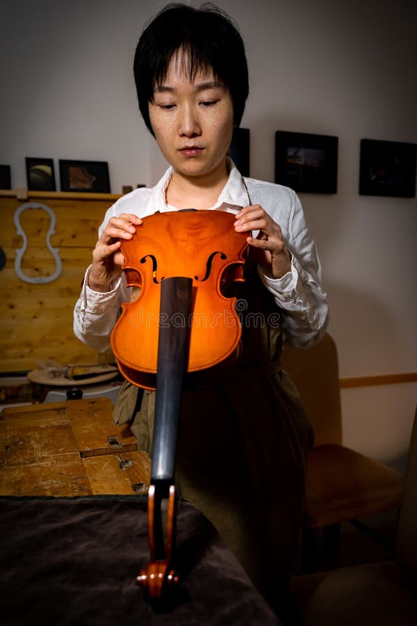 Young Chinese Woman Violin Maker Checking the Quality of Her Violin