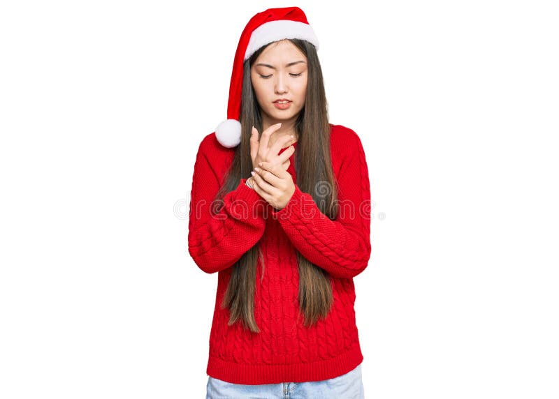 Young chinese woman wearing christmas hat suffering pain on hands and fingers, arthritis inflammation