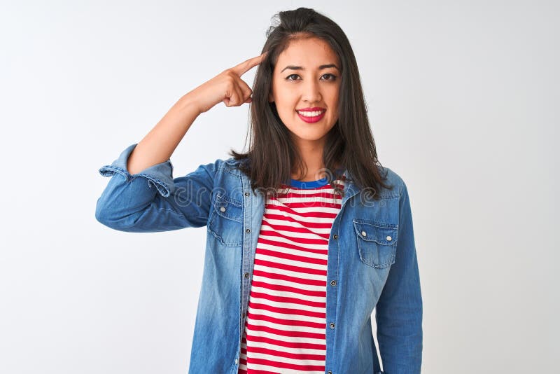 Young chinese woman wearing striped t-shirt and denim shirt over isolated white background Smiling pointing to head with one