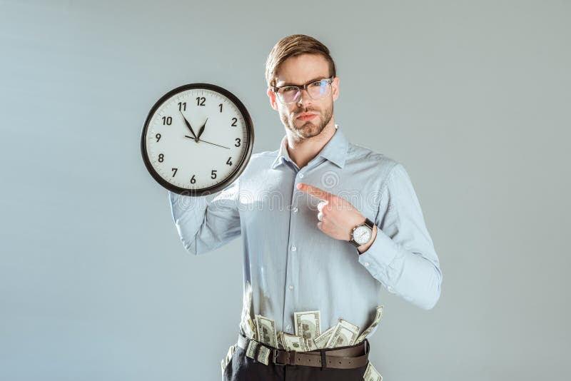 Young confident businessman pointing on clock royalty free stock photos Young confident businessman pointing on clock royalty free stock photos