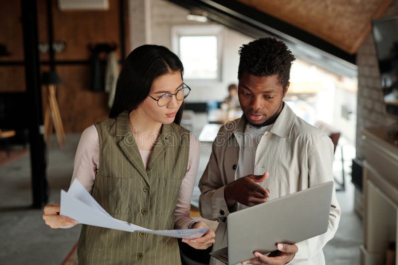 Young confident male analyst pointing at screen of laptop in his hands stock photography