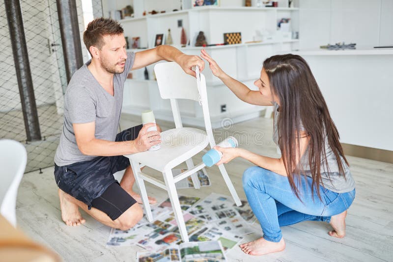 Young couple paints chair together as upcycling