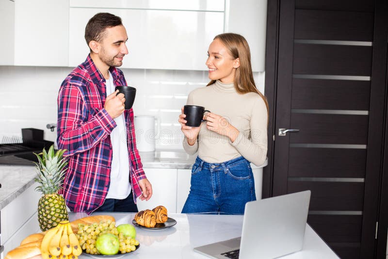 Young couple in bathrobe at home having coffee and eat croissant in the kitchen royalty free stock photo