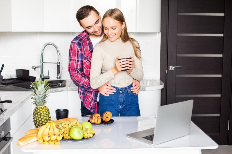 Young couple in bathrobe at home having coffee and eat croissant in the kitchen royalty free stock image