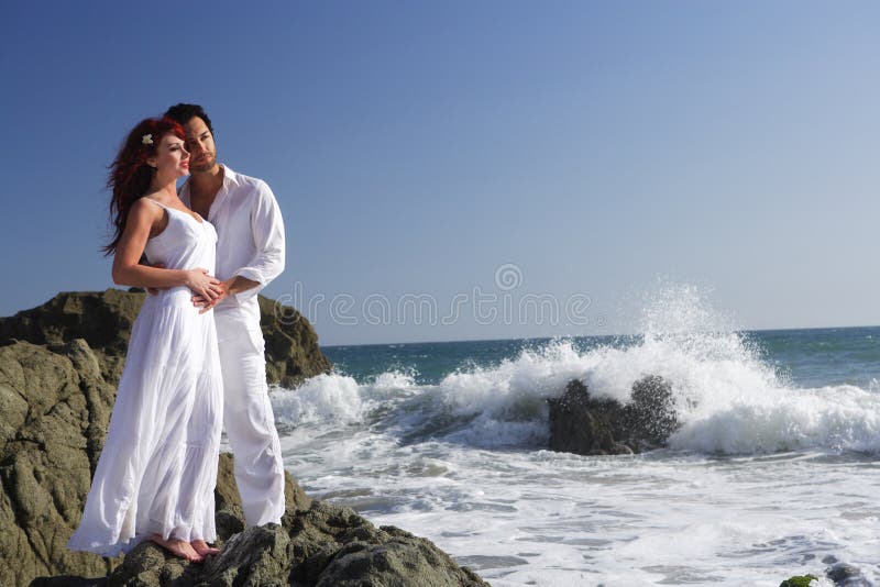 Young couple at the beach standing on rocks