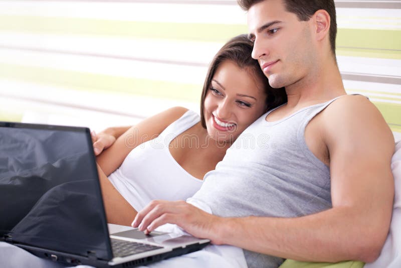 Young couple browsing the internet from their own bed.