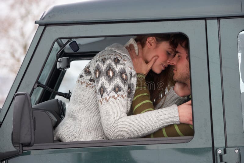 Young couple in car in snow embracing