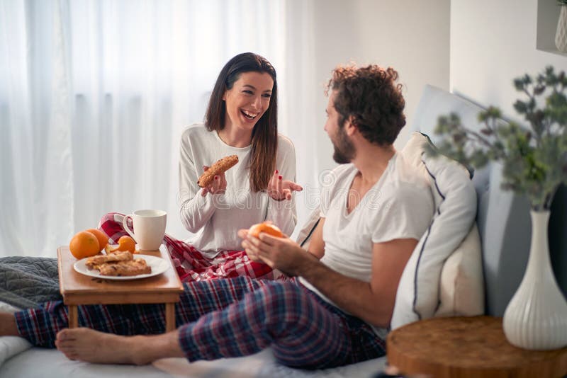 A young couple chatting while having a breakfast in the bed at their bedroom. Love, relationship, together. A young couple chatting while having a breakfast in the bed at their bedroom. Love, relationship, together