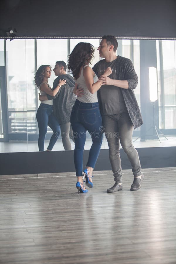 Young couple dancing social danse kizomba in class background.