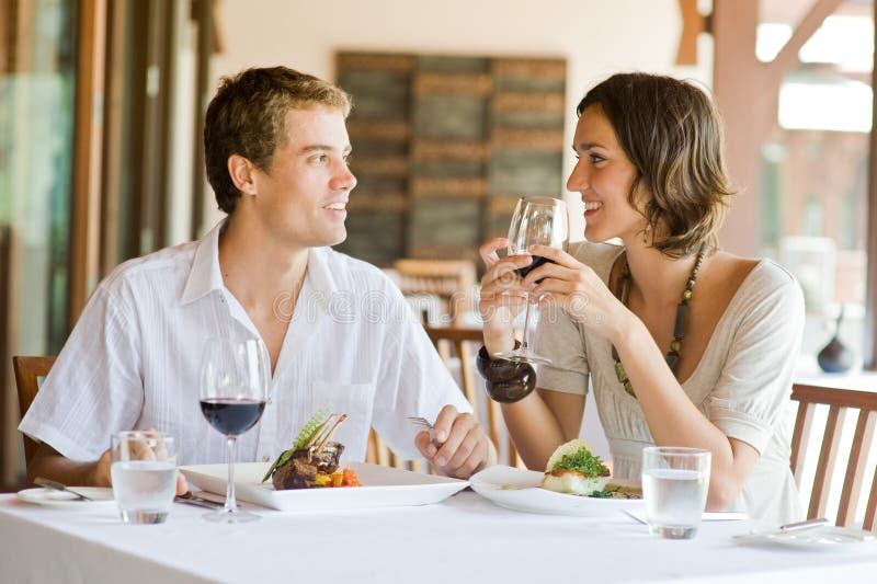 Una giovane coppia seduta ad un tavolo presso un ristorante all'aperto.