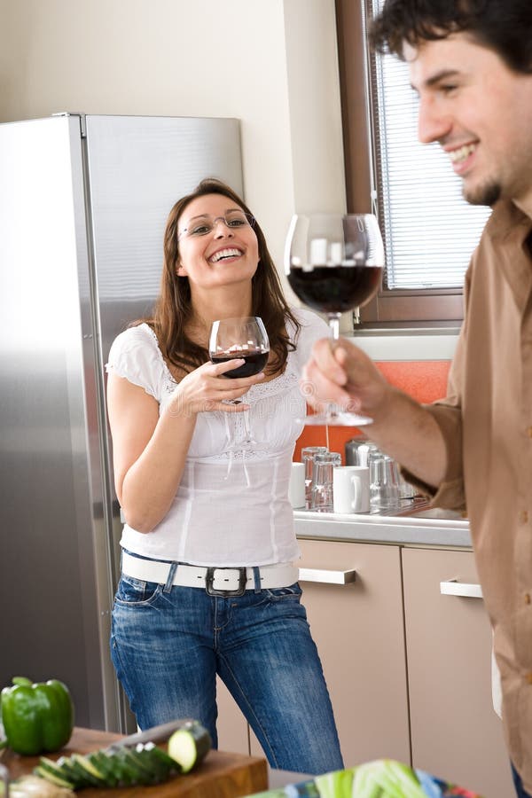 Young couple drink red wine in modern kitchen