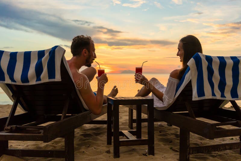 Young couple drinking cocktails on a beach at sunset during vacation stock image Young couple drinking cocktails on a beach at sunset during vacation stock image