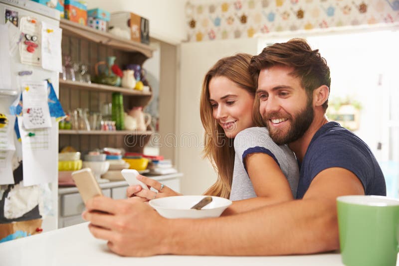 Young Couple Eating Breakfast Whilst Using Mobile Phones royalty free stock images