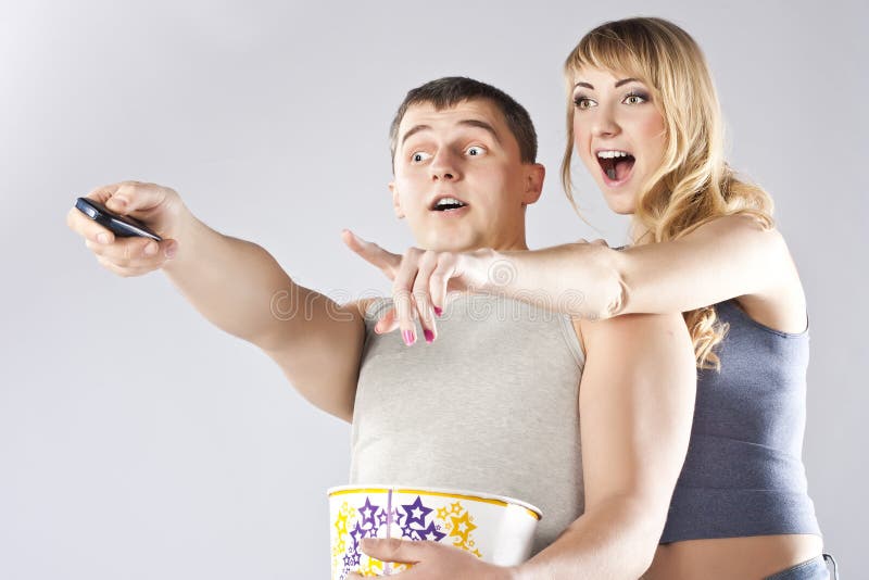 Young couple eating popcorn, watching TV