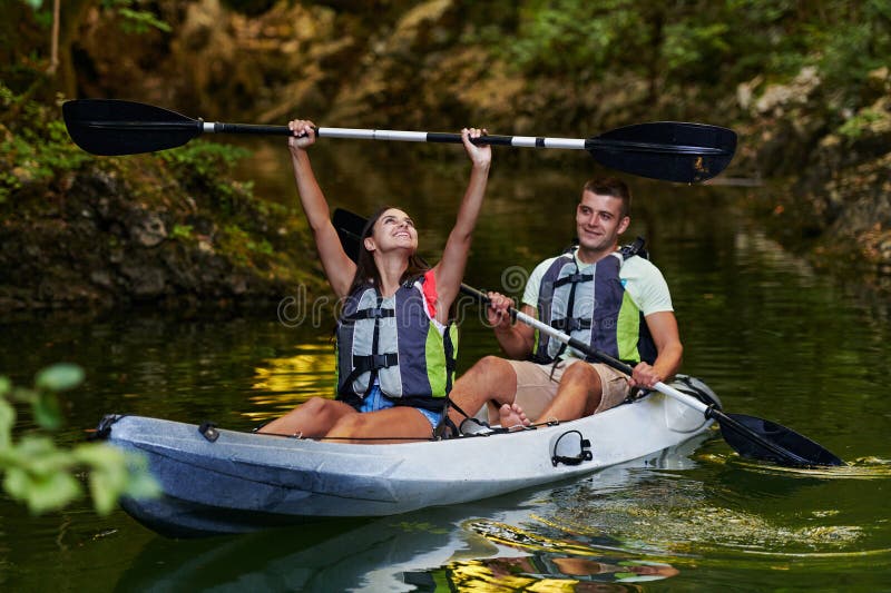 A young couple enjoying an idyllic kayak ride in the middle of a beautiful river surrounded by forest greenery stock photos