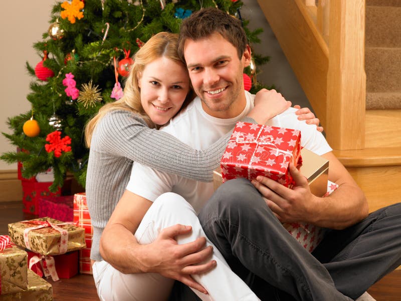 Young couple with gifts in front of Christmas tree