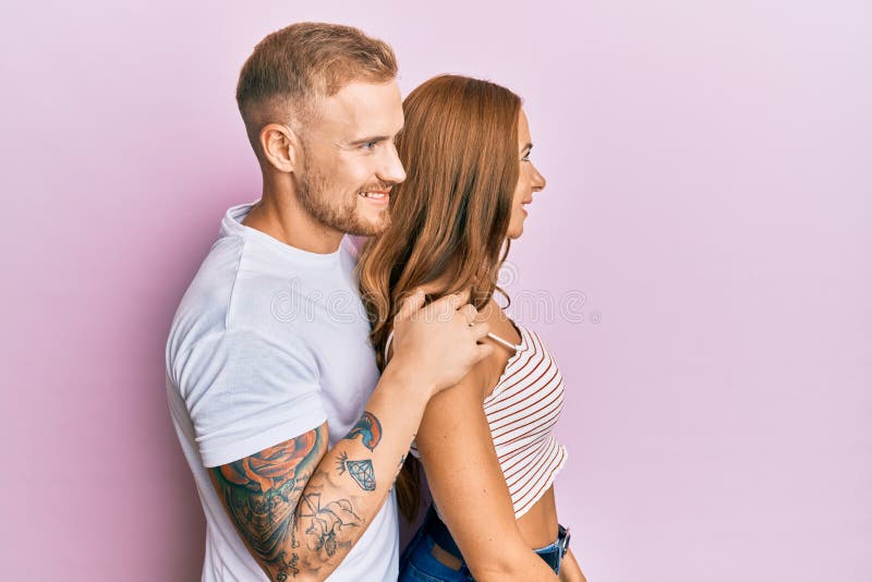 Portrait of a happy young couple in an amusement park at night. Boyfriend  and girlfriend are looking at camera while standing against the carousel  stock photo (275365) - YouWorkForThem