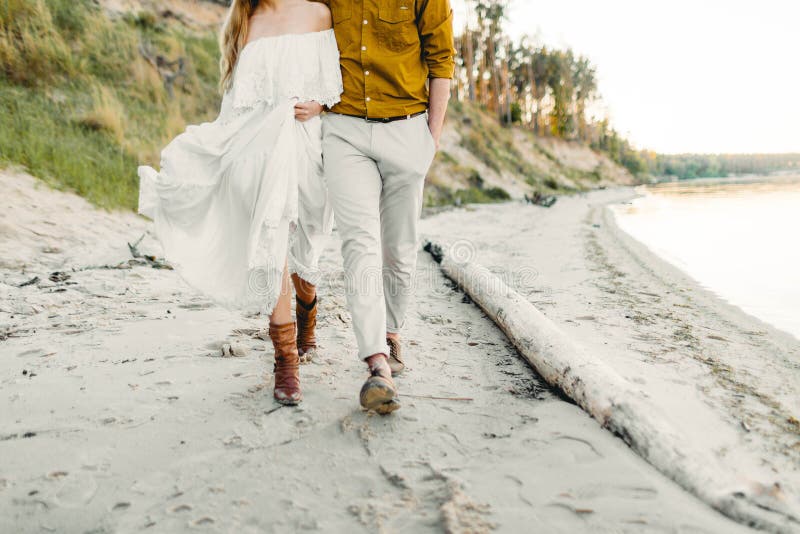 A young couple is having fun and walking on the sea coastline. Newlyweds looking at each other with tenderness. Romantic date on the beach. Wedding. Artwork, soft focus