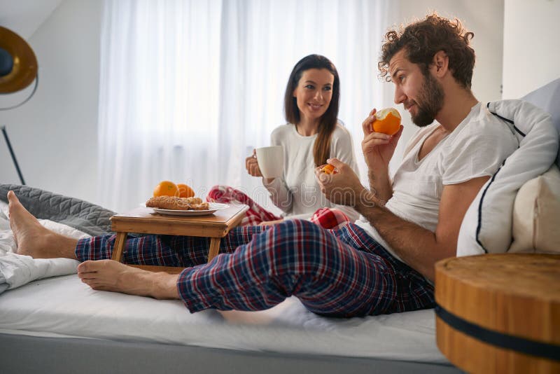 A young couple having a tasty food for a breakfast in the bed at their bedroom. Love, relationship, together. A young couple having a tasty food for a breakfast in the bed at their bedroom. Love, relationship, together