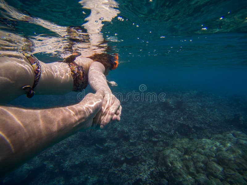 Follow me concept of a young couple snorkeling in the sea. Clear blue water