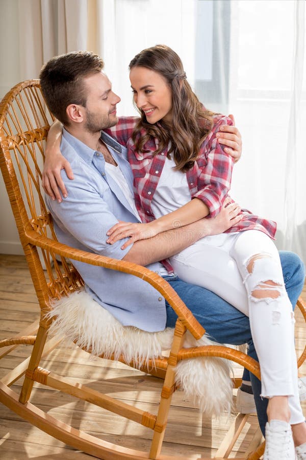 Young couple hugging in rocking chair and looking at each other.