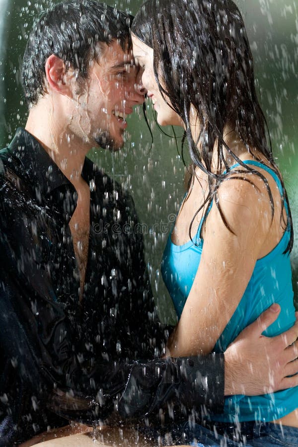 Young couple hugging and smiling under a rain, in passion stock images.