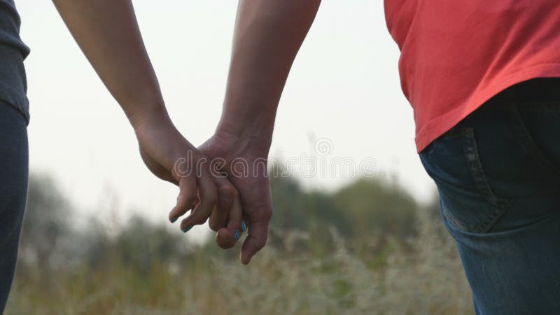 Young couple joining hands outdoor. Man and woman taking arms on nature background. Male and female hands comforting and stroking each other. Symbol of love and devotion. Romantic outside. Close up.