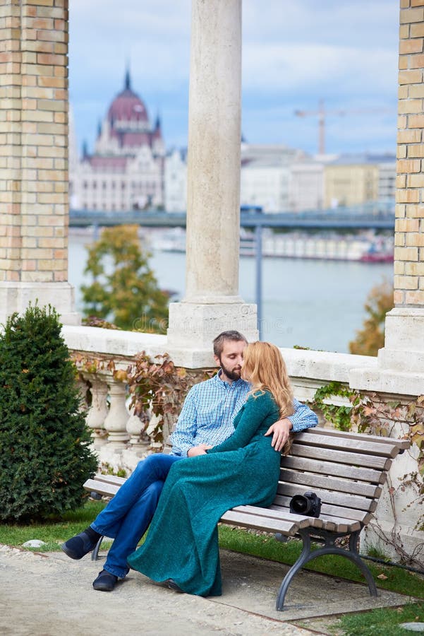 Young couple kissing on bench near the columns of Budapest