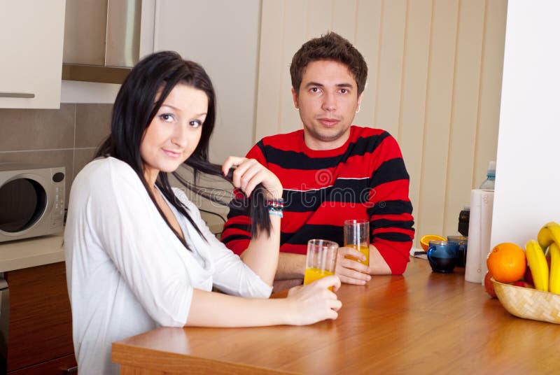 Young couple in kitchen drink juice