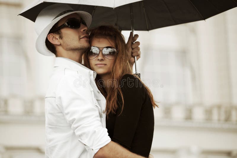 Young fashion man and woman in love with umbrella in the rain. Young fashion man and woman in love with umbrella in the rain