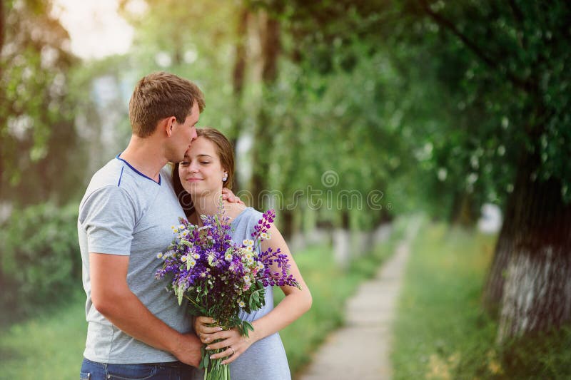 Young Couple in Love with a Bouquet of Flowers on a Background of the
