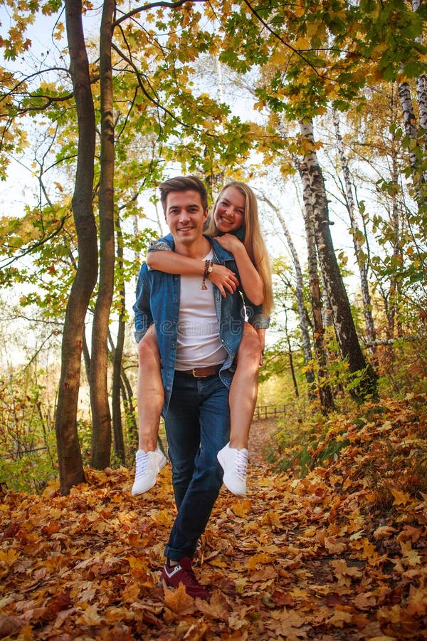 Young couple in love happily walk together in beautiful autumn park, colorful nature, leisure activity outdoors