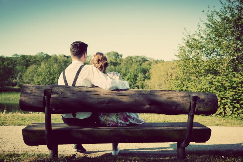 Young couple in love sitting on a bench in park. Vintage royalty free stock image Young couple in love sitting on a bench in park. Vintage royalty free stock image