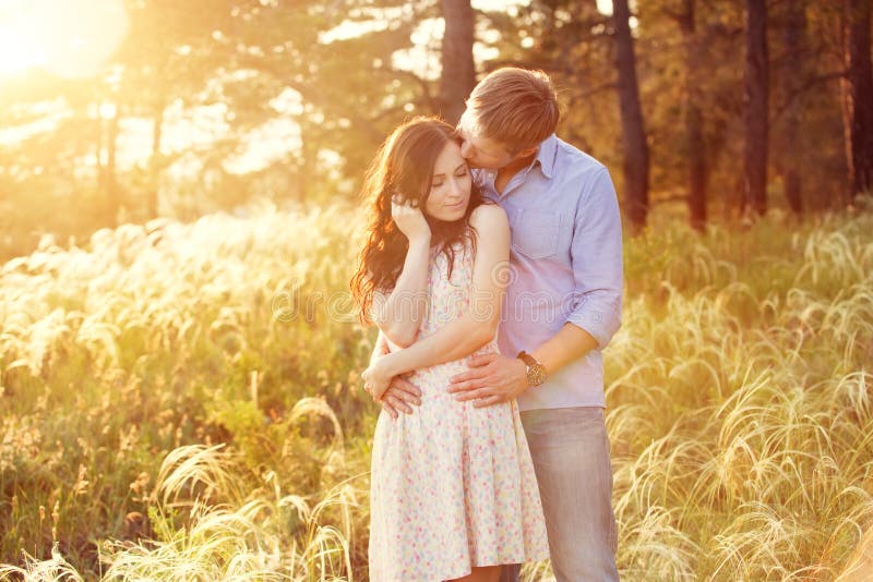 Young couple in love at sunset at the field